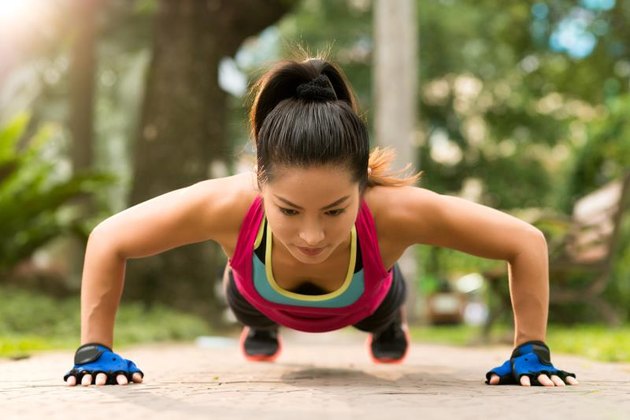Sporty woman doing push-ups outdoors