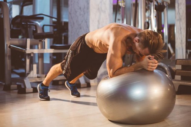 Young Fitness Man is Doing Planks on Pilates Ball
