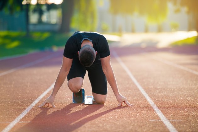 Athletic man on track starting to run. Healthy fitness concept with active lifestyle