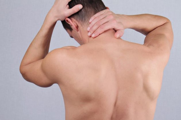 Man with neck and back pain. Man rubbing his painful back close up. Pain relief concept