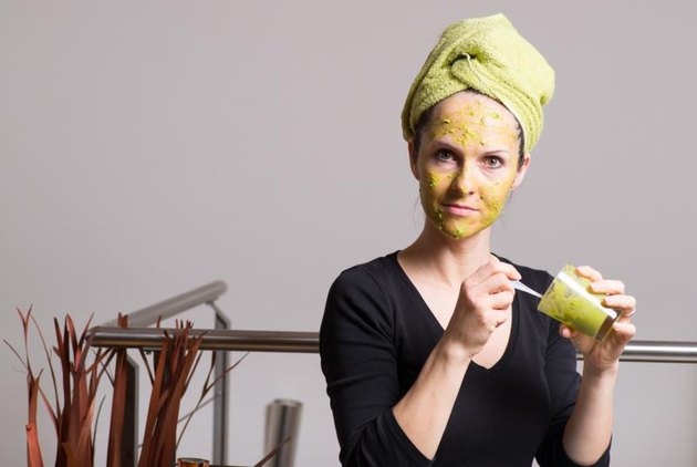 Attractive young woman with spots using a facial avocado mask