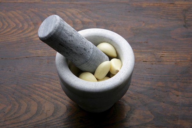 Mortar and pestle with cloves of garlic, high angle view