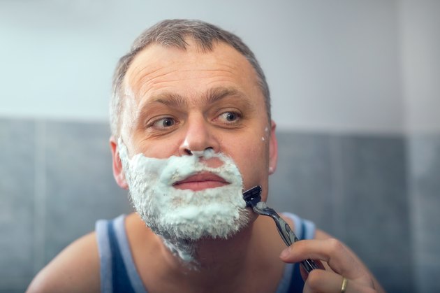 Middle aged man shaving in bathroom