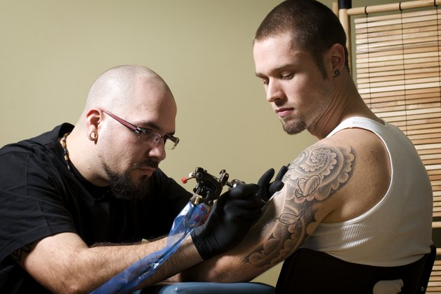Tattooer concentrating on giving someone a tattoo