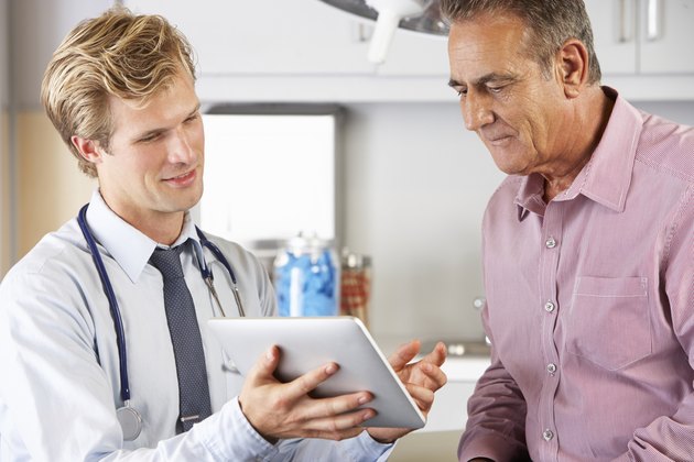 Doctor Discussing Records With Patient Using Digital Tablet