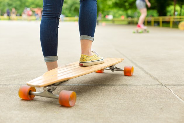 Teenage girl practicing riding long board.