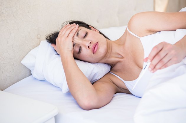 Pretty brunette watching thermometer on bed