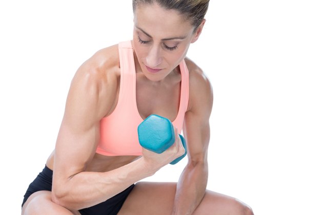 Strong woman doing bicep curl with blue dumbbell