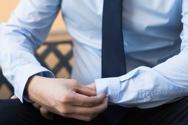Young man in business office shirt buttoning his sleeve buttons