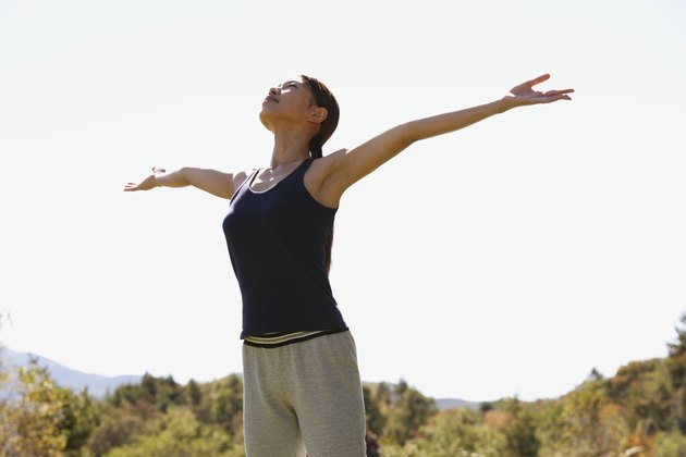 Young woman standing with arms outstretched, low angle