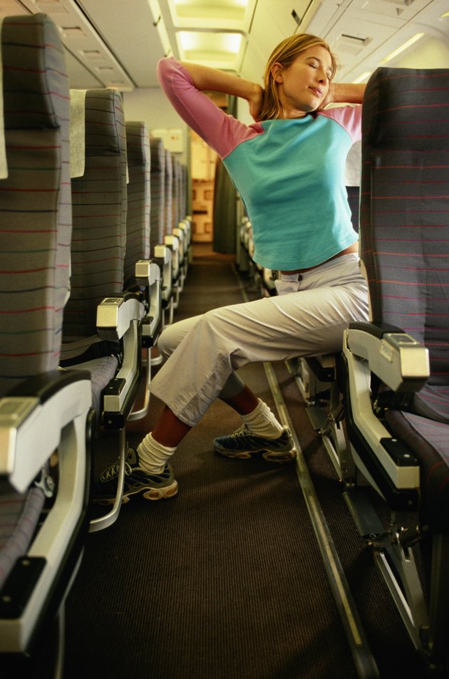 Woman in airplane with hands behind head, eyes closed