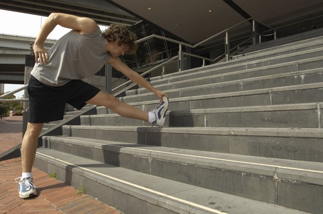 Young man stretching leg on steps, side view