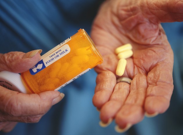 Senior woman holding bottle and medication, close-up of hand