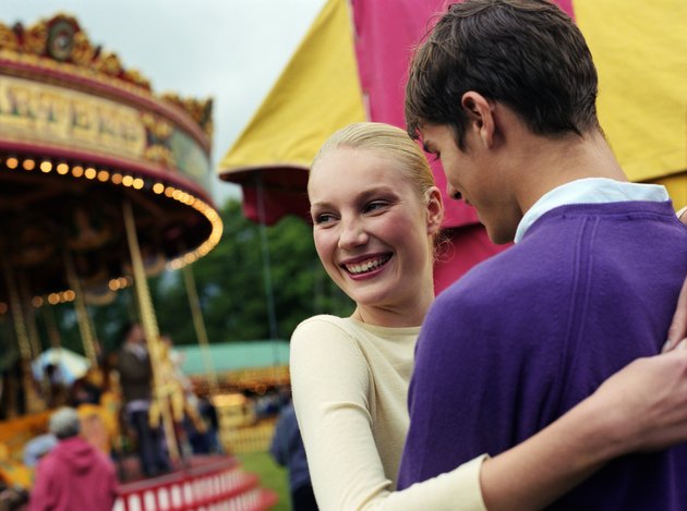 Young couple embracing at fairground, smiling, close-up