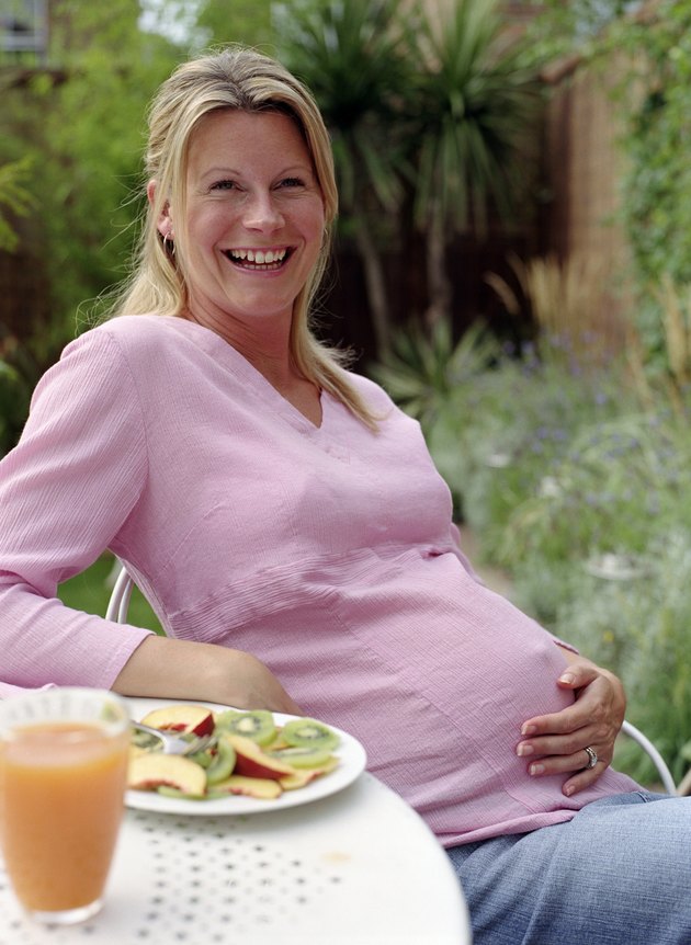 Pregnant woman at breakfast table outdoors, smiling, portrait