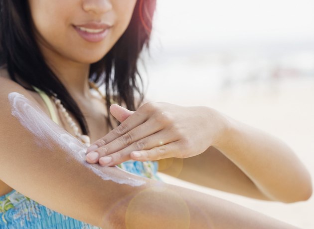 Mid section of woman applying lotion to arm