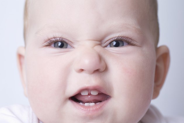 Baby boy pulls funny face with scrunched up nose