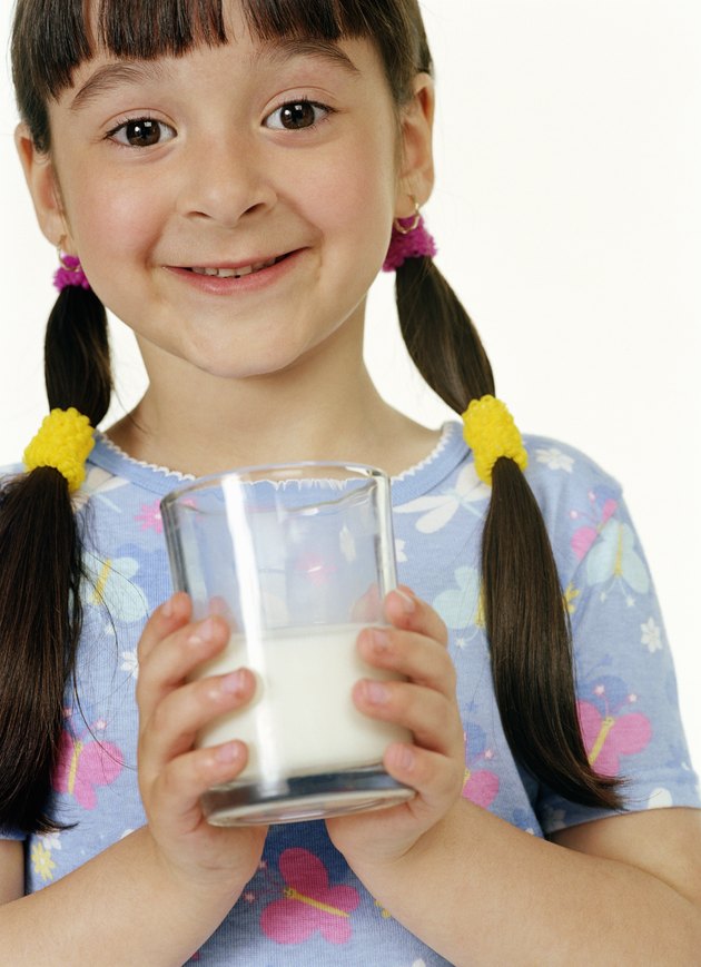 Girl (4-6) holding glass of milk, smiling, portrait