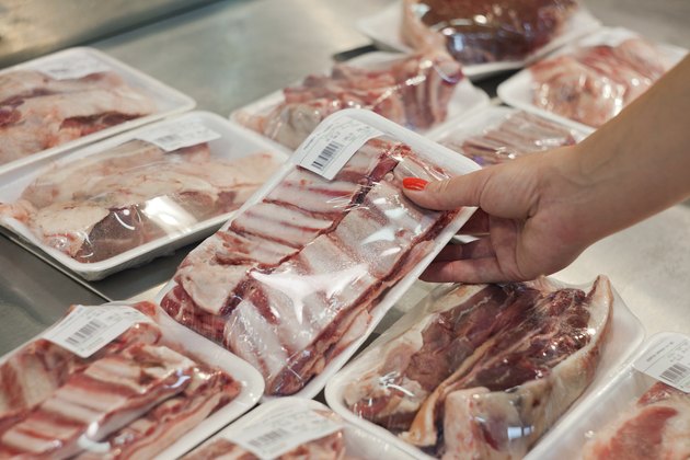 Packaged meat with woman hand in the supermarket