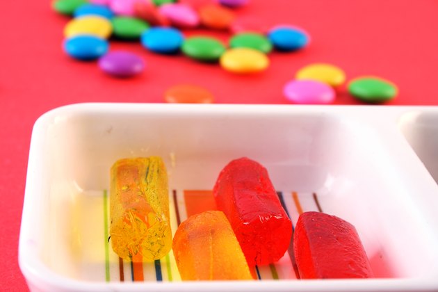 Fruit candies arranged in a tray and few candies scattered in the background