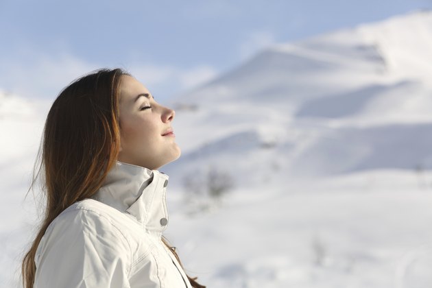 Wman breathing fresh air in winter in a snowy mountain