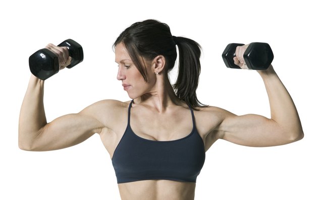 medium shot of an adult woman in a sports bra as she lifts up two dumbbell weights