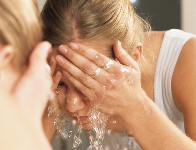 beautiful woman splashing face with water with reflection