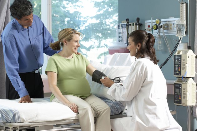 Side profile of a female doctor checking the blood pressure of a pregnant woman