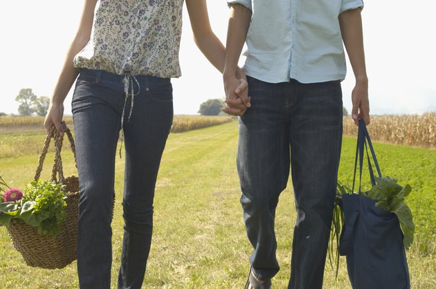 Young couple carrying bags, holding hands, mid section