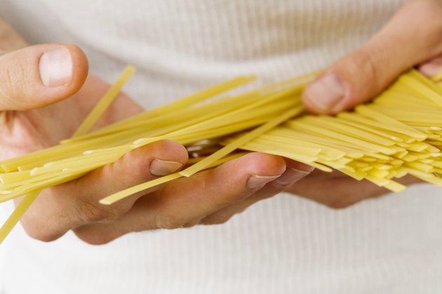 Close-up of uncooked spaghetti in a man's hands