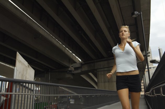 Young woman jogging under fly-over, low angle view