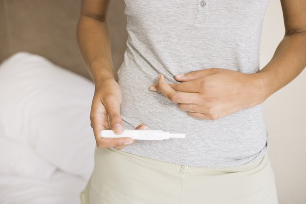 Woman crossing fingers with pregnancy test