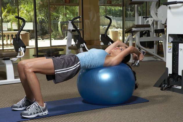 Woman exercising with dumbbells on fitness ball