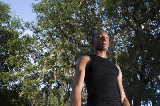 Low angle view of a young man standing under the trees