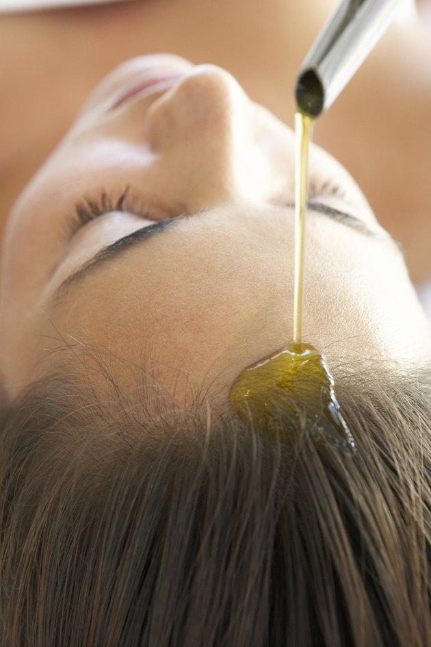 Oil pouring onto woman's forehead and hair