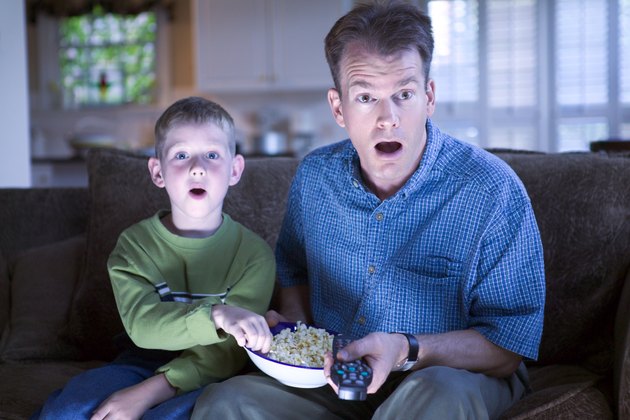 Father and son with remote control and popcorn