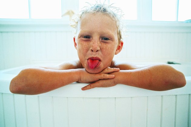 portrait of a young girl (6-8) in a tub sticking out her tongue