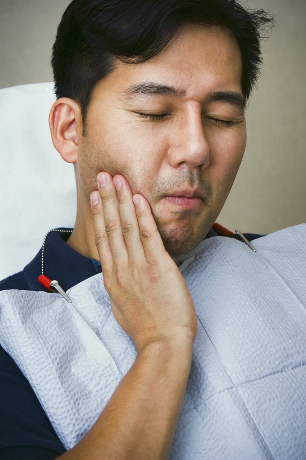 Male dental patient holding jaw