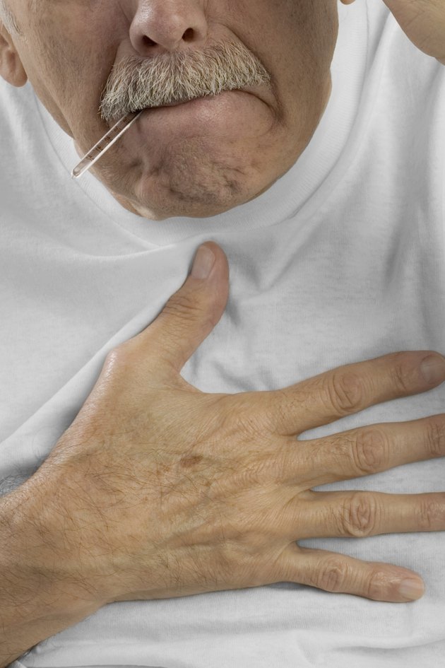 Senior man with hand on chest and thermometer in mouth