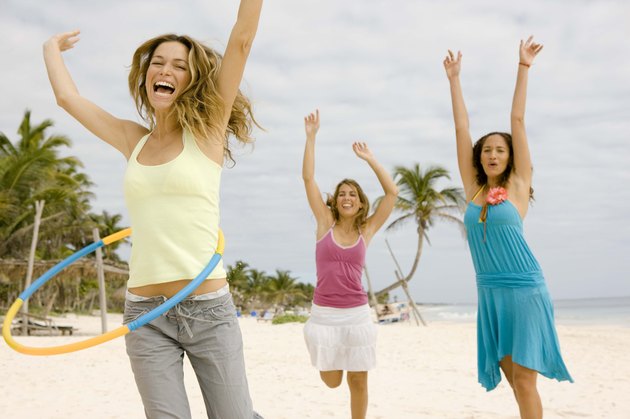Women playing with plastic toy hoop on beach