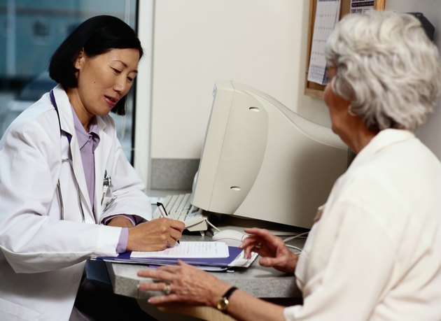 Doctor writing prescription for mature female patient