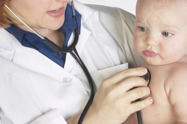Doctor holding and monitoring baby with stethoscope