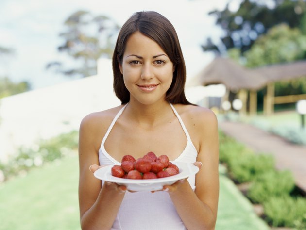 Portrait of a young woman holding a plate of strawberries