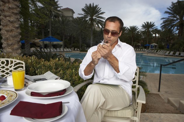 Man lighting cigarette by swimming pool