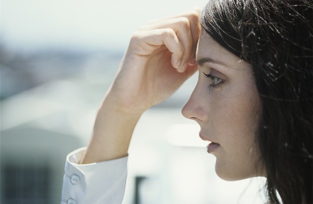 Young woman with hand on forehead outdoors,close-up,profile