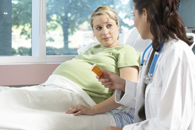Side profile of a female doctor giving a bottle of pills to a pregnant woman