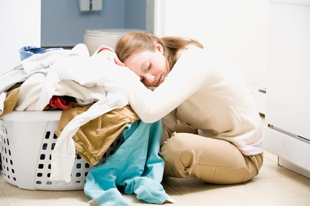 Overwhelmed woman with basket of laundry on floor