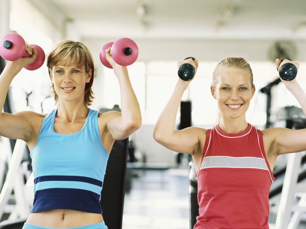 Two young women exercising with dumbbells in the gym