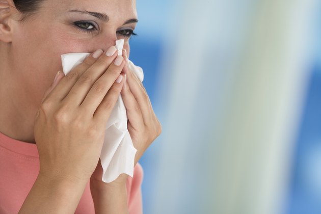 Woman blowing nose into tissue