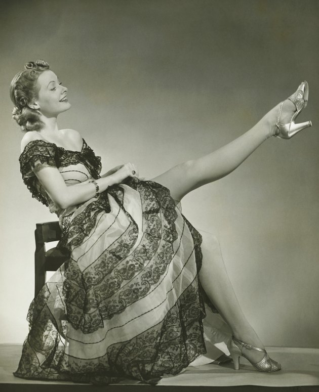 Glamorous woman in evening gown showing leg, portrait, (B&W)